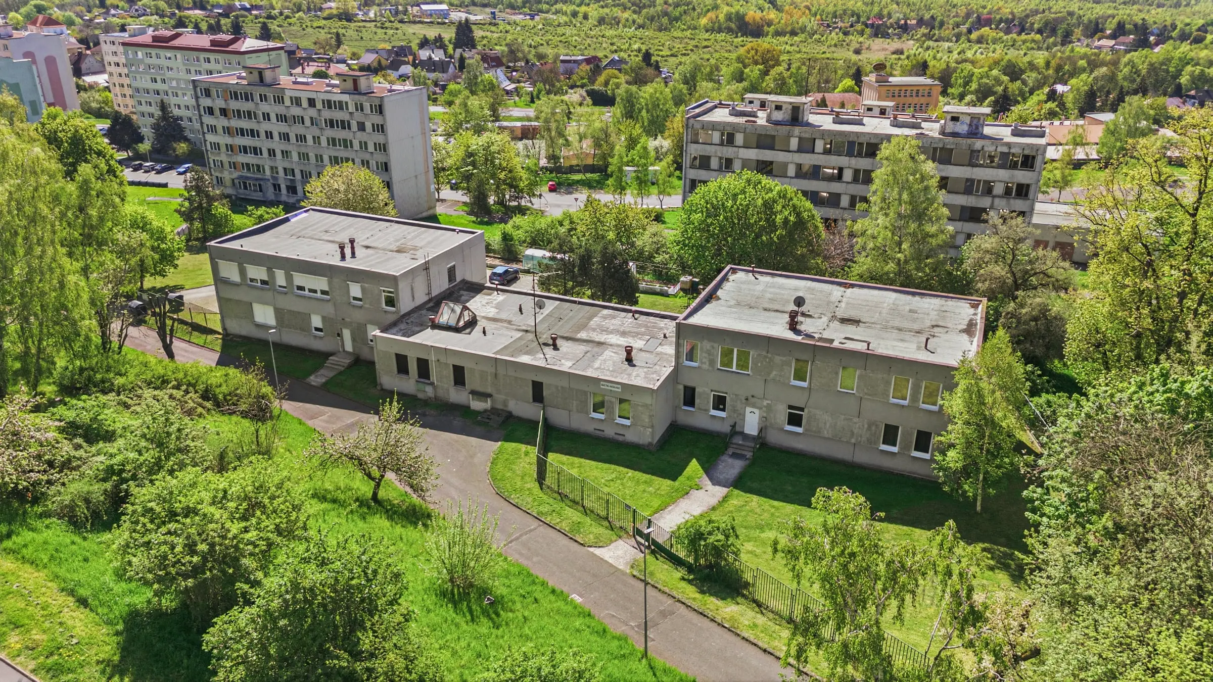 Budovy ubytovny z dronu, přístupová cesta a zeleň kolem areálu